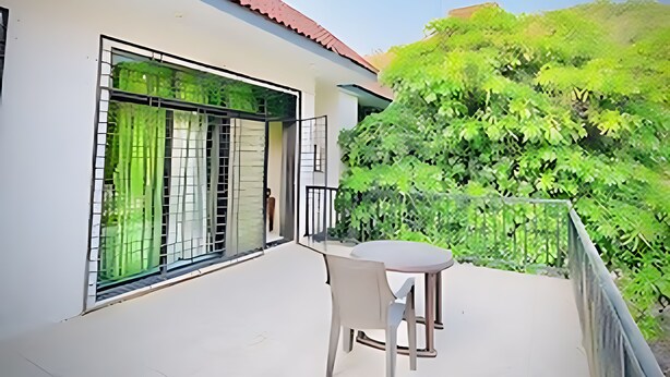 Ein Balkon mit Tisch und Stuhl, ein Fenster mit grünen Vorhängen und ein rot gefliester Dachboden.