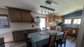 Une cuisine avec des meubles de rangement en bois, une table à manger avec des chaises, un four à micro-ondes et une cuisinière.