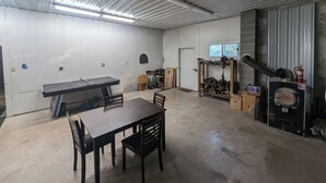 Un grand espace intérieur comprenant une table de ping-pong, des chaises, une table en bois, une cheminée et une fenêtre.