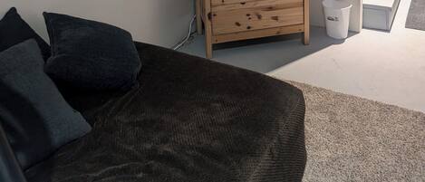 Una sala de estar con un televisor de pantalla plana en la pared, un aparador de madera, un sofá con cojines y un cuadro de osos.