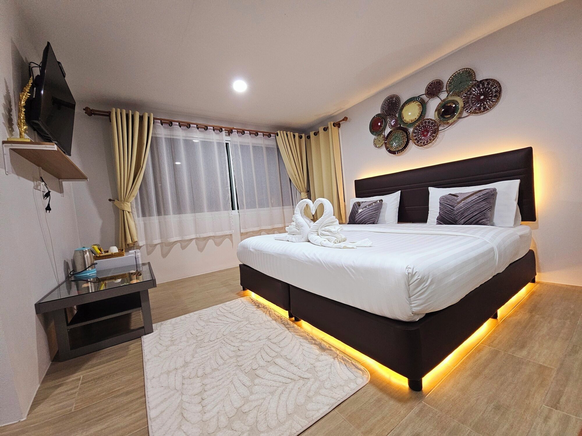 Une chambre d’hôtel moderne avec un grand lit, une table de chevet, une télévision et un élément décoratif mural.