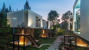 Un espace extérieur moderne doté de passerelles surélevées, de coins salon et d’un jardin bien éclairé.