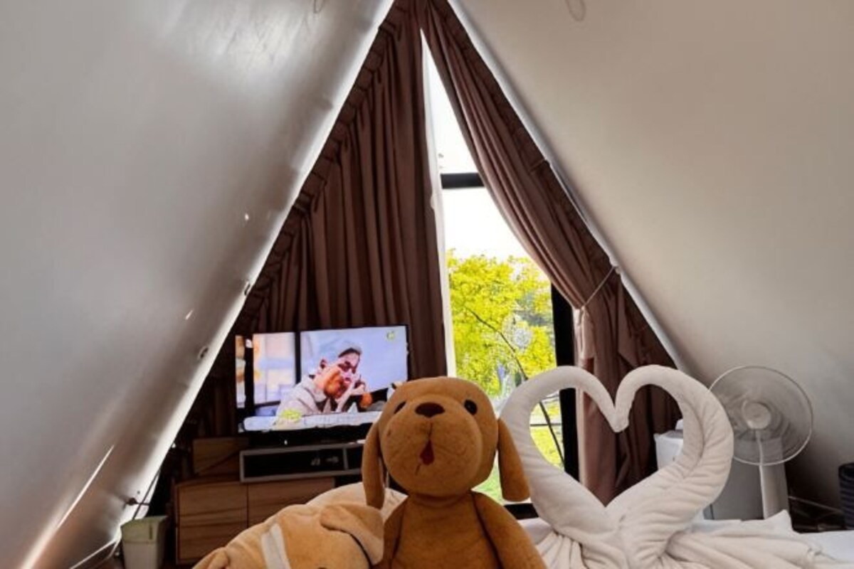 A room with a television, a large teddy bear, and a heart-shaped decoration.