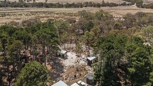 An aerial view of a rural property with scattered buildings, dense pine forests, and open fields. - Bilby Park Escape 1 by Tiny Away (Black Range)