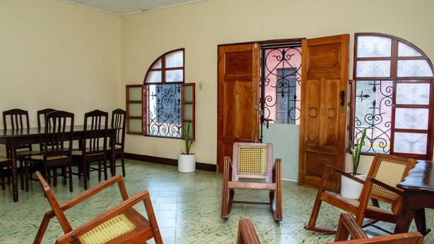 A room with wooden furniture, including a dining table and chairs, and a rocking chair.