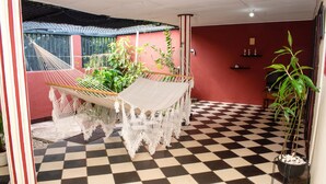 A checkered floor, a hammock, and potted plants in a room with red walls.