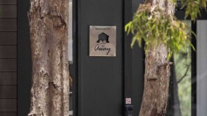 Una puerta negra con un letrero que dice "Managed by Away" y un símbolo de prohibido fumar.
