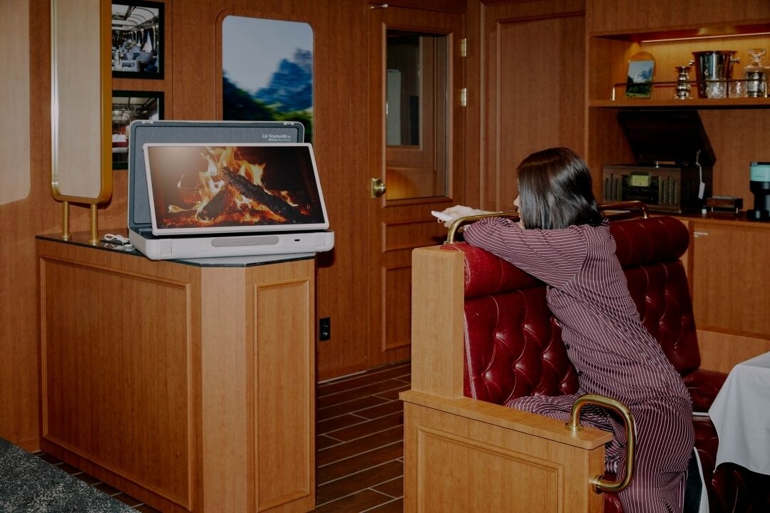 A room with a wooden cabinet, a television displaying a fire, and a red leather chair.