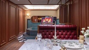 A dining area with a red upholstered booth, a checkered floor, and a table set with glassware and plates. - Stay Passport Express Spa Dangsan (Seoul)