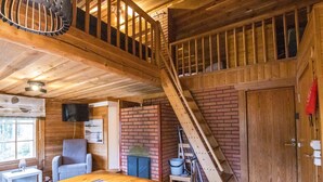A rustic cabin interior with a wooden dining table, a staircase, and a brick wall. - Terwa-ukko 2 by Interhome (Hyrynsalmi)