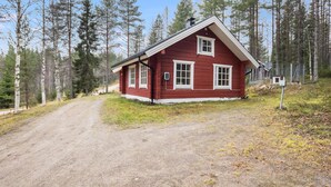 A red cabin with white trim, surrounded by a forest and a dirt road. - Terwa-ukko 2 by Interhome (Hyrynsalmi)