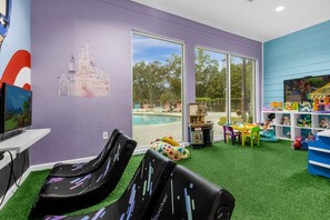 A room with a pool view, a children's play area, and a large window. - Cozy 4BR Disney vacation Home 7-104 (Kissimmee)