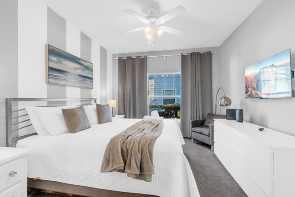 A modern hotel room with a large bed, a desk, a chair, and a ceiling fan.