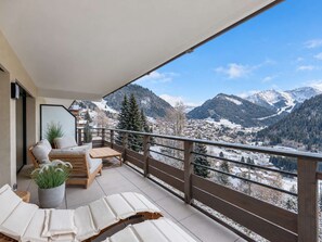 Un balcone con ringhiera in legno, un divano, un tavolo e poltrone relax.