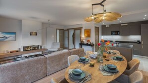 A modern living room with a dining area, a kitchen, and a fireplace. - THELEME 102 (CHATEL)