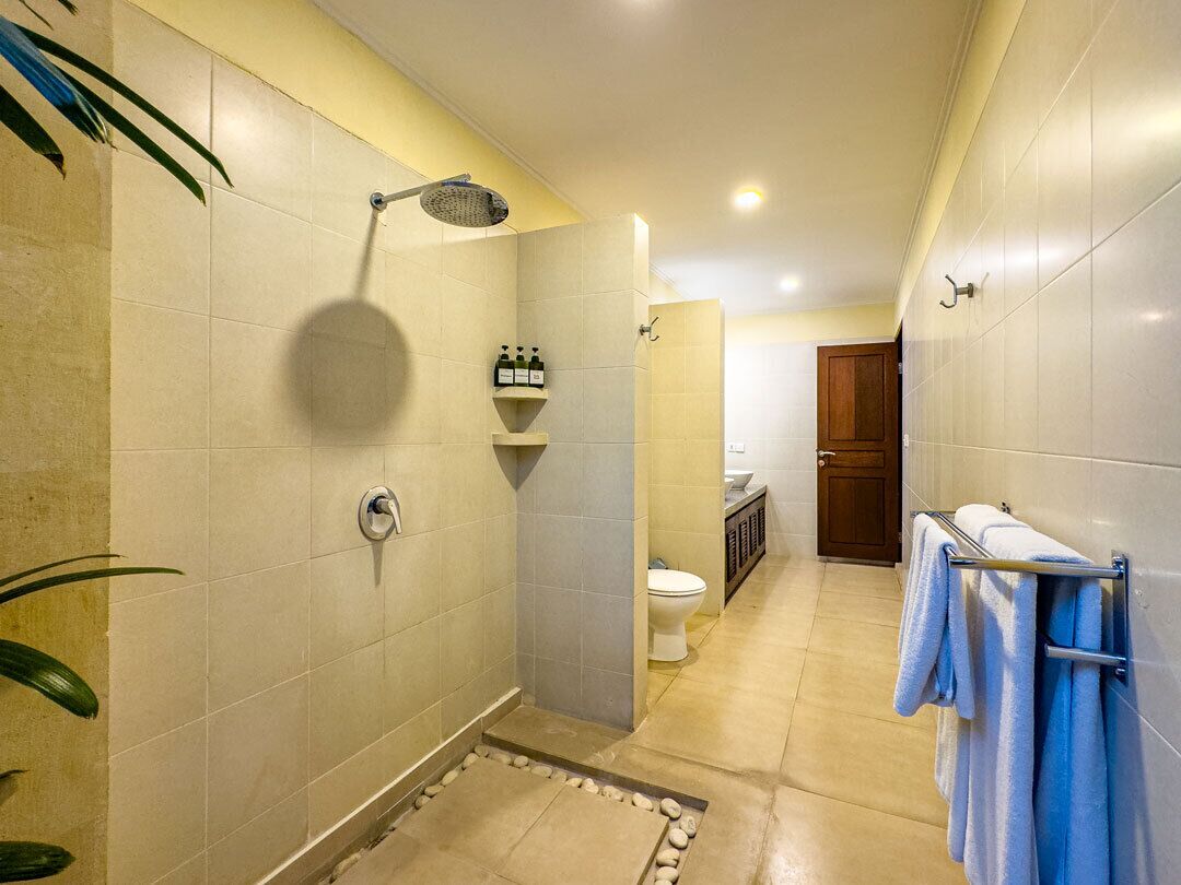 A bathroom with a shower, toilet, sink, and towel rack.