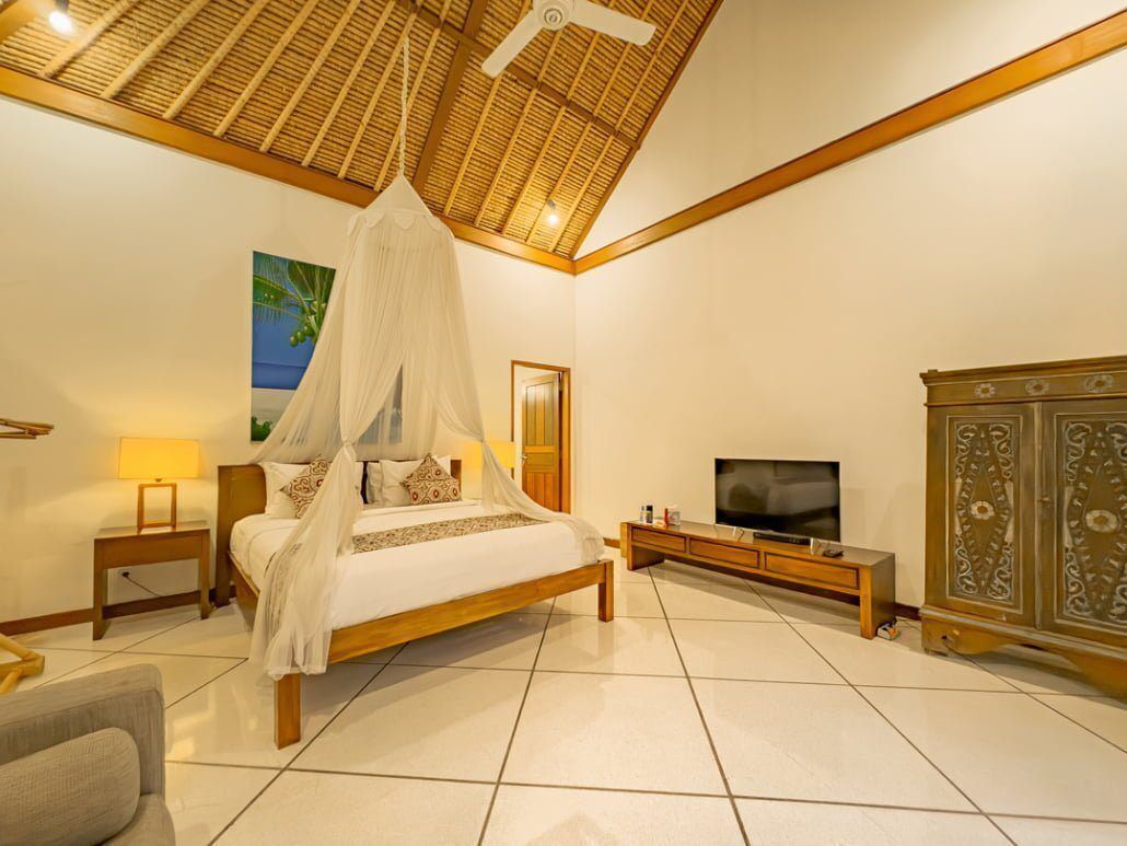 A bedroom with a bed, TV, cabinet, and a ceiling fan.