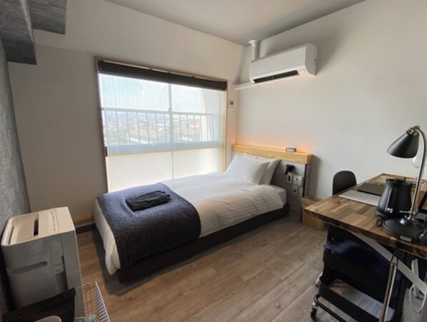 Cozy retreat with a single bed, desk, and window offering a view of the outside.