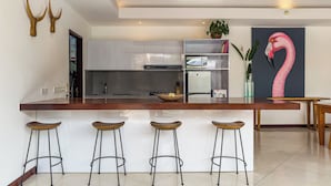A modern kitchen with a central island, bar stools, a microwave, and a refrigerator. - Villa Bugis Kayu Aya Seminyak (Seminyak)