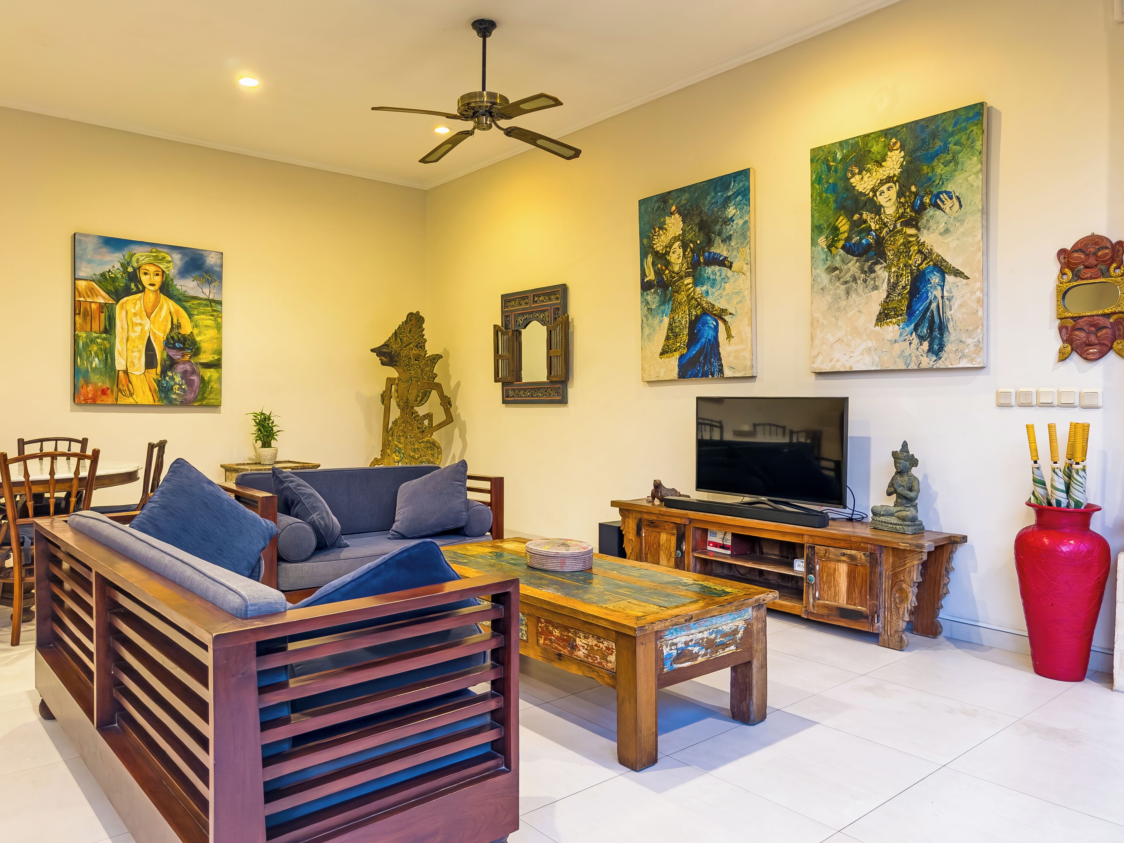 A living room with a sofa, coffee table, TV, and artwork on the walls.