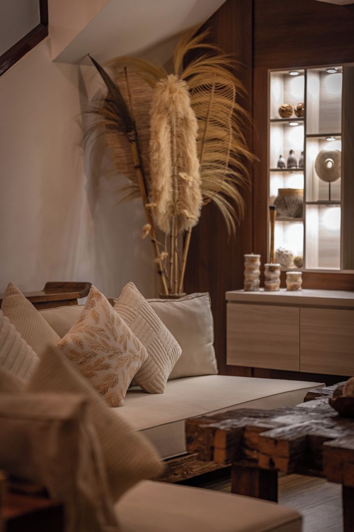A cozy living room with a sofa, decorative pillows, a wooden coffee table, and a tall plant.