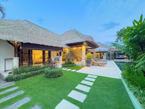 A resort with thatched-roof villas, a swimming pool, and a well-maintained garden.