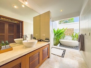 Une salle de bain moderne avec deux vasques, un grand miroir et une baignoire sur pieds.
