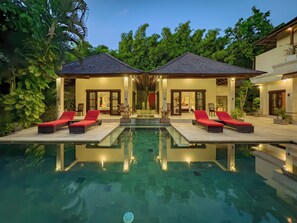 A luxurious poolside area with two separate buildings, each with a balcony and a door leading to a bedroom. - Villa Bugis Abimanyu Seminyak (Seminyak)