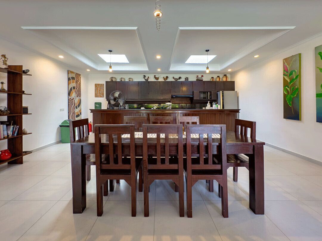 A modern kitchen with a central island, wooden chairs, and a dining table.