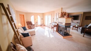 A living room with a fireplace, a piano, and a sofa. - The Lakeside Retreat (Aberdeen)