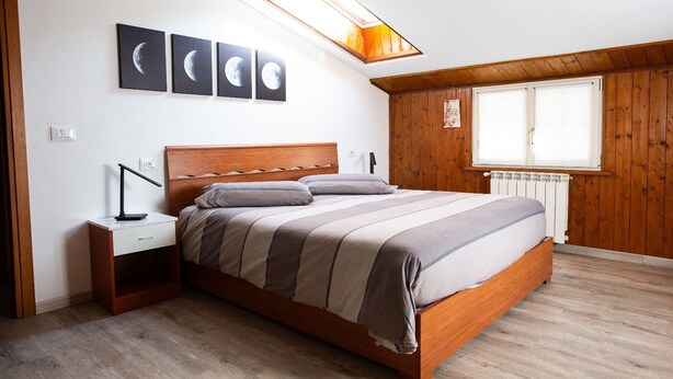 Un dormitorio con una cama de madera, una mesita de noche, un escritorio y un tragaluz.