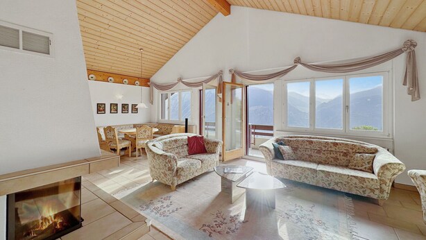 Amplia sala de estar con chimenea, techo de madera y ventanas grandes que ofrecen vistas a la montaña.