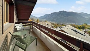 Un balcón con vistas a las montañas, una mesa y sillas.