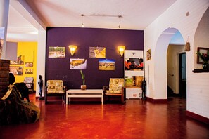A spacious lobby with a red floor, a reception desk, and a seating area with patterned chairs. - Ilboru Safari lodge (Arusha)