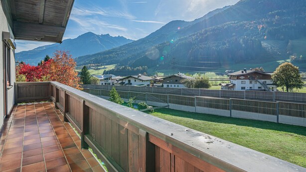 Ein Balkon mit Blick auf eine Berglandschaft, einschließlich Häusern und einem See.