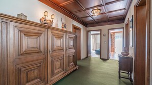 Ein Korridor mit Holzvertäfelung, einem grünen Teppich und einer Decke mit Holzbalken.