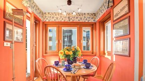 A dining area with a round table, chairs, a vase with flowers, and framed pictures on the walls. - Appartamento Fraiteve Ski In Ski Out 300m (Sestriere)