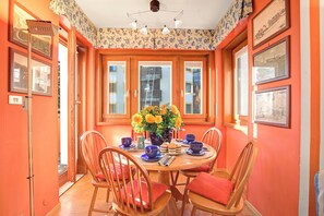 A dining area with a round table, chairs, a vase with flowers, and framed pictures on the walls. - Appartamento Fraiteve Ski In Ski Out 300m (Sestriere)