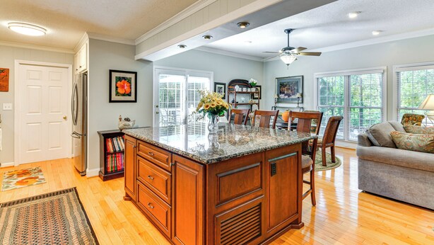 A spacious kitchen with a large island, wooden cabinets, and a dining area with chairs. - 1 Mi to Dtwn: Home w/ Fire Pit & Deck in Hudson! (Hudson)