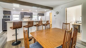 A modern kitchen with dark cabinets, a wooden dining table, and bar stools. - < 1 Mi to Dwtn: Valparaiso Family Home (Valparaiso)