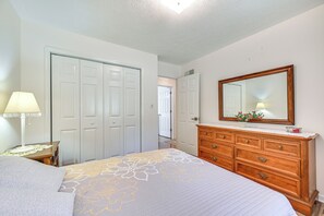 Quarto com cama, penteadeira, espelho e porta.