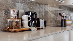 Eine Küchenarbeitsplatte mit Kaffeemaschine, Toaster, weißer Tasse und einem Glasbehälter.