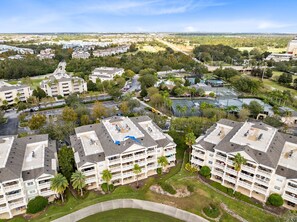 A multi-story hotel with balconies, a parking lot, and surrounding greenery. - Modern resort condo close to amusement parks (Reunion)