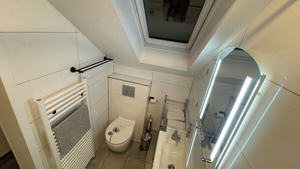 A compact bathroom with a toilet, sink, and shower.