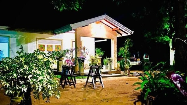 A house with a covered patio area, potted plants, and a vehicle parked outside. - Sanora Hostel (Sigiriya)