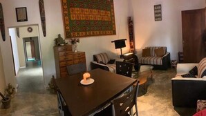 A cozy living room with a wooden table, two sofas, a coffee table, and a bookshelf. - Sanora Hostel (Sigiriya)
