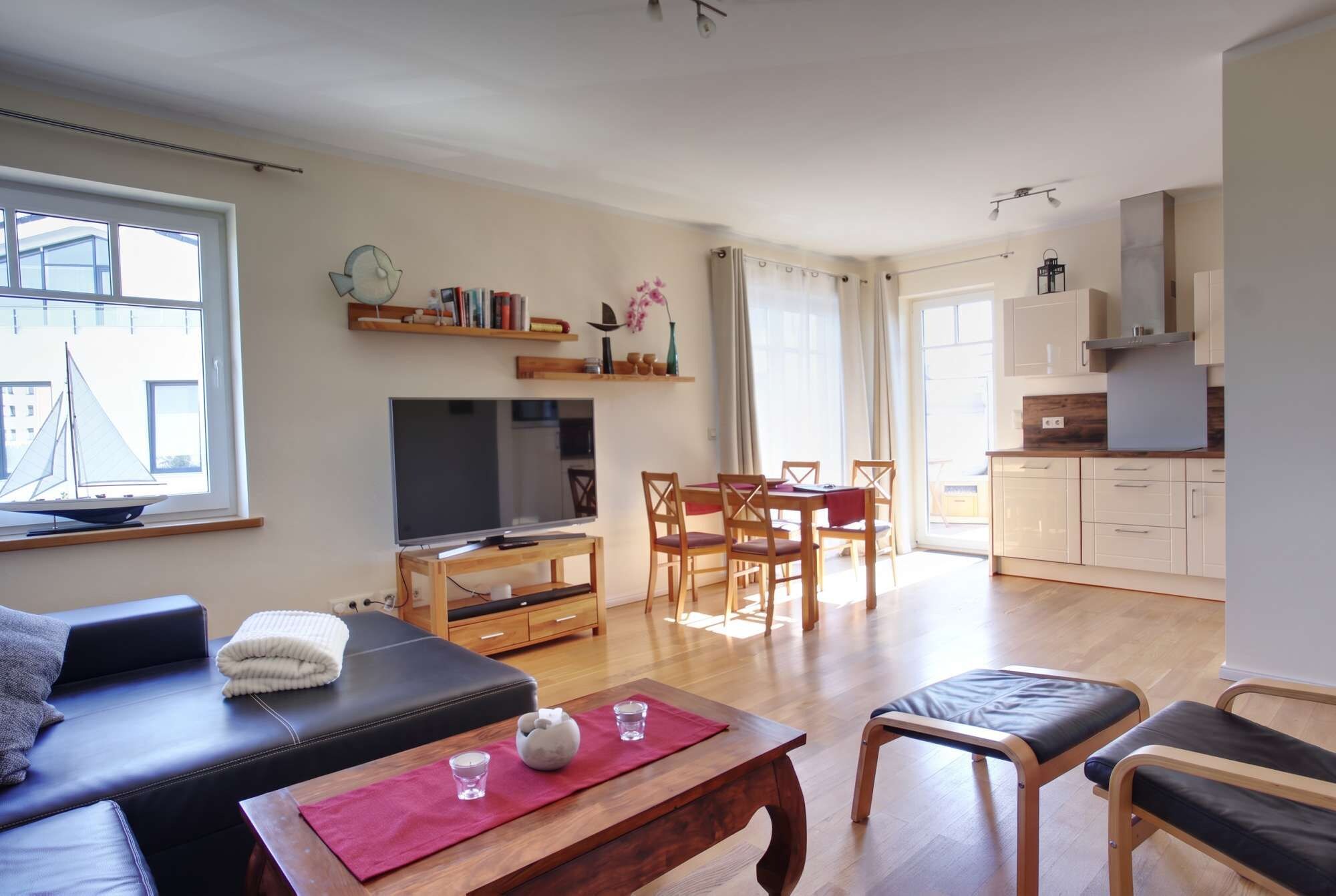 A living room with a sofa, TV, and a dining area with chairs and a table.