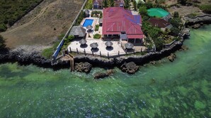 Vista aérea de una propiedad costera con piscina, varias construcciones y un litoral rocoso.