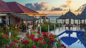 Un resort con piscina, asientos al aire libre y vista al océano.