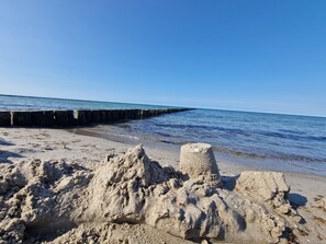 Una playa arenosa con una estructura de hormigón y un cielo azul despejado.